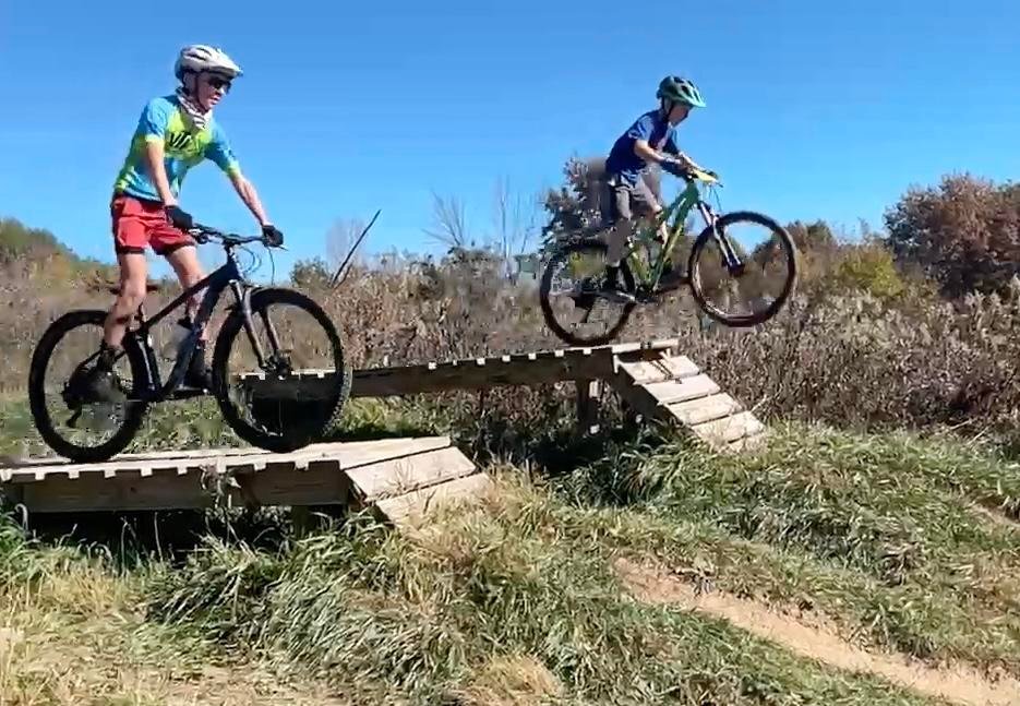 Youth on mountain jumping off of wooden drops.